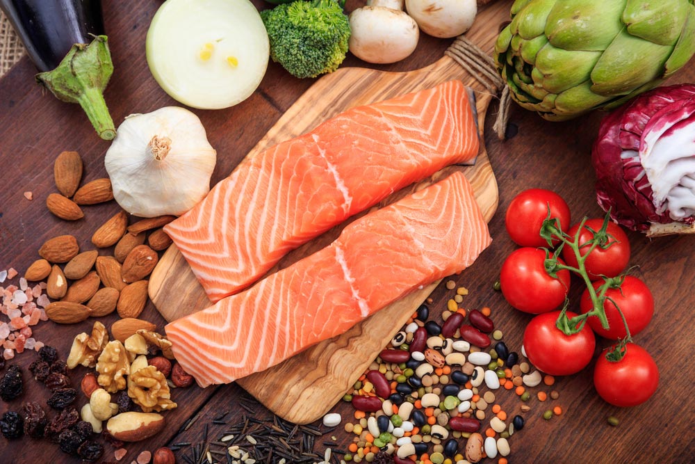 roher Lachs mit frischem Gemüse, Nüssen auf Holztisch