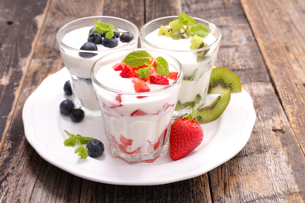 Naturjoghurt mit frischen Früchten im Glas auf einem weißen Teller