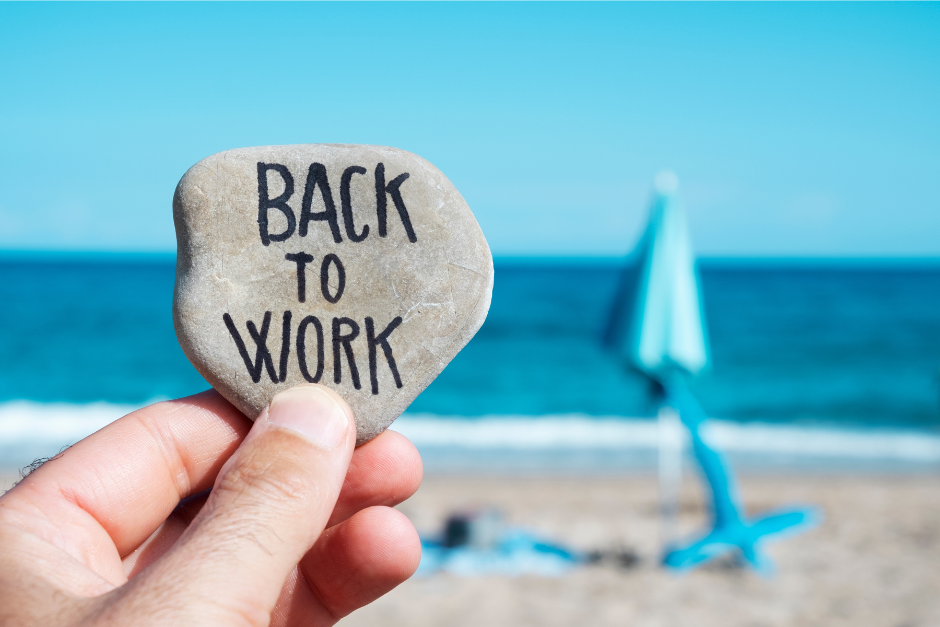 Stein mit Aufschrift "Back to work" vor Strandkulisse